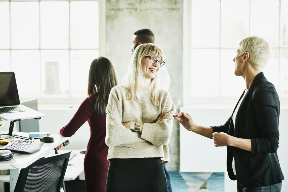 two-blond-woman-chatting-and-smiling-in-the-office-how-to-be-more-persuasive