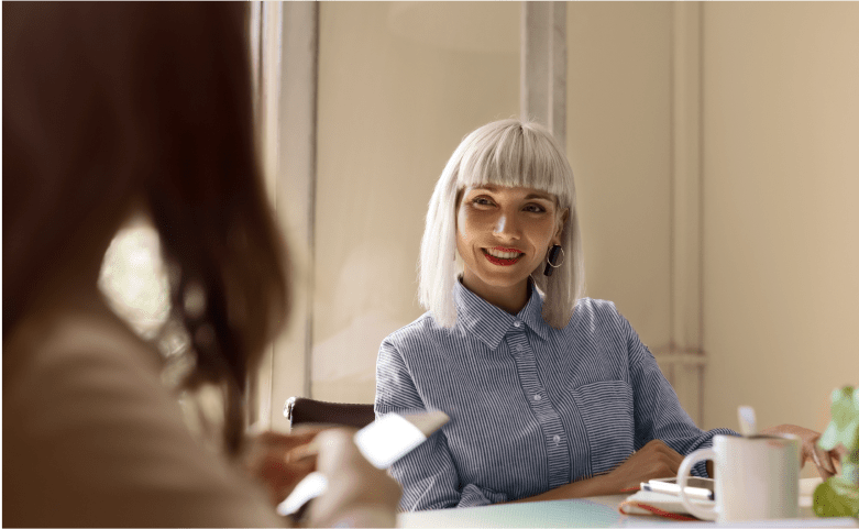 woman in blue shirt with white hair talking to someone